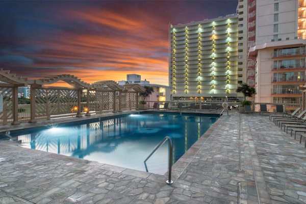 Experience a relaxing evening swim in the expansive shared outdoor pool, located on a spacious stone-tiled recreation deck that boasts beautiful sunset views.