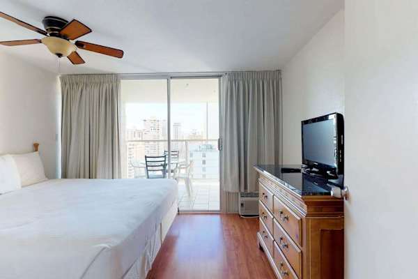 Wake up to natural light and stunning elevated views in this private bedroom, complete with a flat-screen TV, a classic wooden dresser, and direct sliding glass door access to the outdoor balcony.