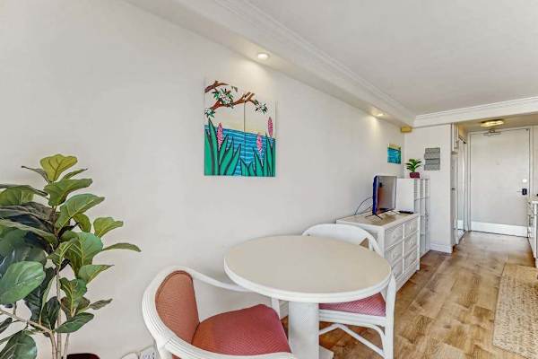 The entryway features a cozy seating spot, tropical artwork, and sleek wood-style flooring.