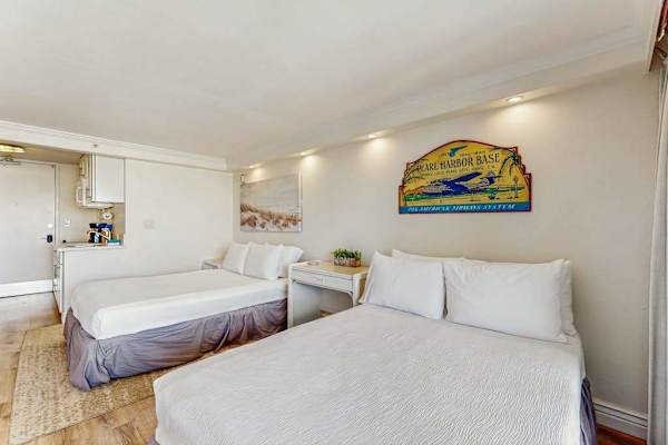 A welcoming sleeping area is outfitted with two full sized beds, ambient lighting, and tropical wall decor.