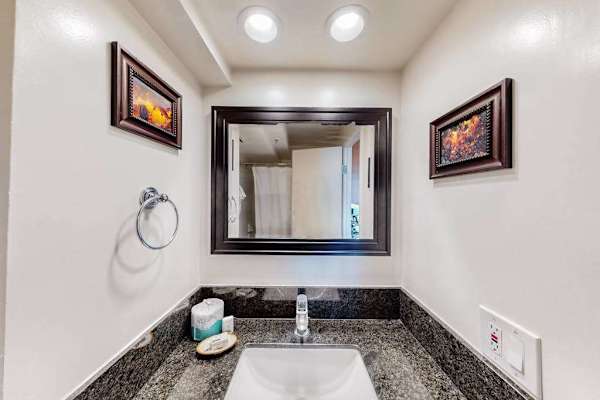 The bathroom vanity features a dark granite countertop, an undermount sink, a large framed mirror, and complimentary amenities.