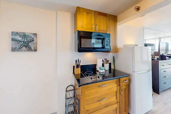 Built-in electric cooktop, microwave oven, custom wood cabinets, and full-size refrigerator. All ready for breakfast.