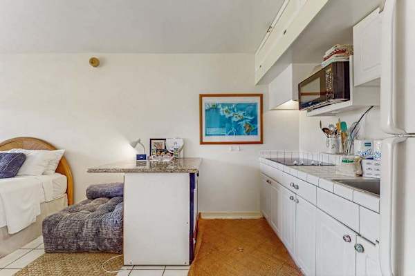 Open kitchen features counters, appliances, artwork, seating, and television nearby