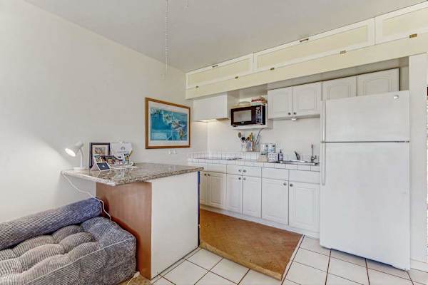 Compact kitchen provides refrigerator, counters, cabinets, and adjoining living space