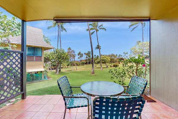 Covered patio dining area overlooks resort gardens, palms, and ocean