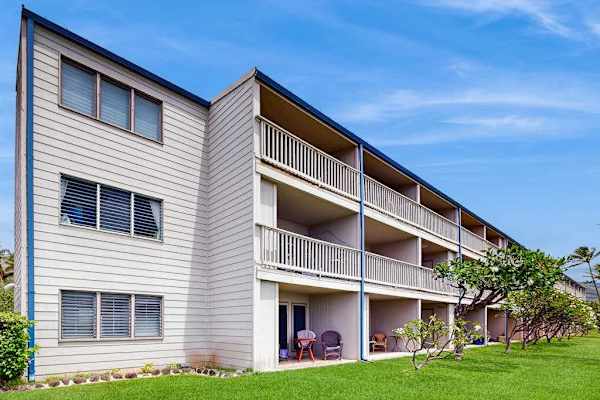 Resort building features balconies, lawns, palms, and sunny island surroundings