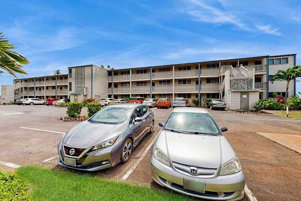Resort building features balconies, lawns, palms, and sunny island surroundings