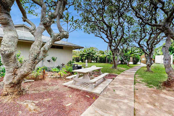 Garden walkway winds past tropical plants, stone paths, and outdoor seating
