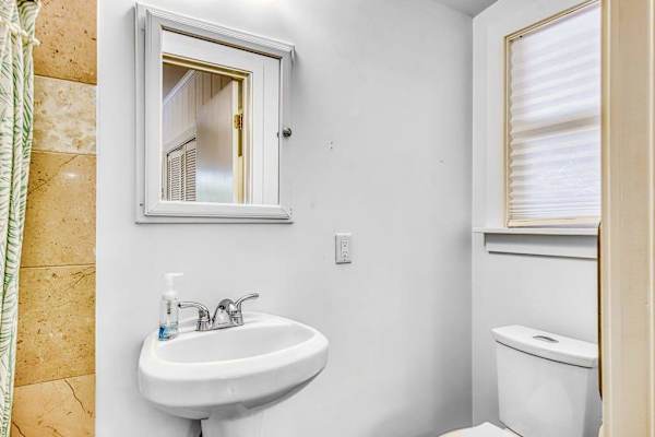 Primary bathroom shower and pedestal sink create a fresh, practical space