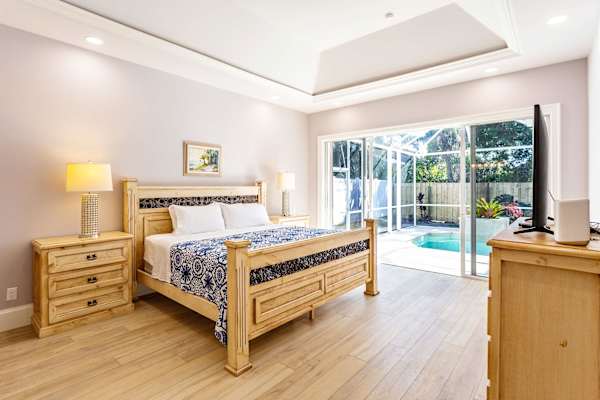 Master bedroom with king bed, tv and entrance to the pool