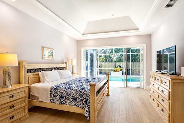 Master bedroom with king bed, tv and entrance to the pool