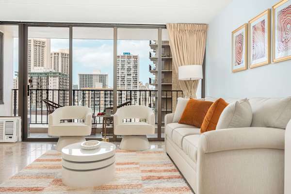 Living room with pull-out sleeper sofa, a rotatable coffee table, and 2 arm barrel chairs with tufted backs.