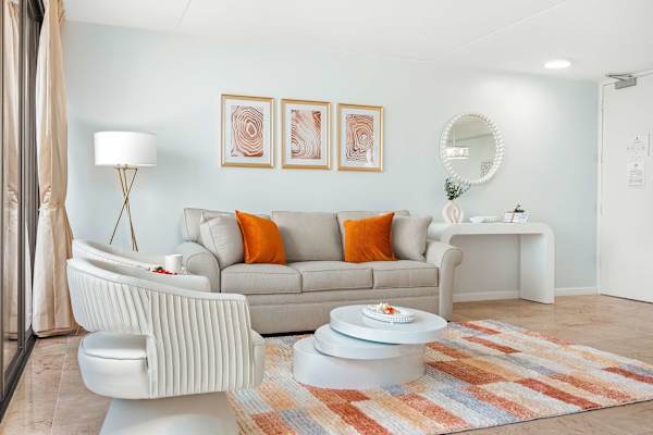 Living room with pull-out sleeper sofa, a rotatable coffee table, and 2 arm barrel chairs with tufted backs.