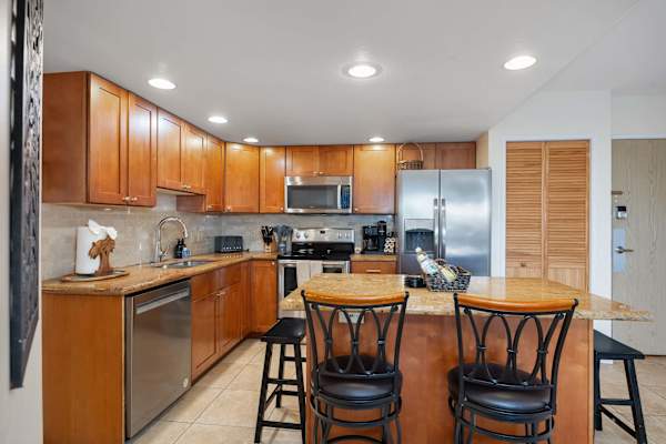A fully appointed stainless‑steel kitchen, complete with a full‑size stove, microwave with range hood, two‑door refrigerator with freezer, and dishwasher—providing the setting for elevated meal preparation and prompt, efficient cleanup.