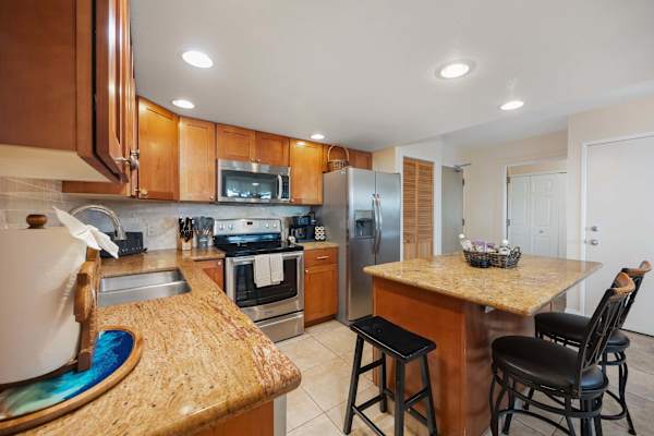 A fully appointed stainless‑steel kitchen, complete with a full‑size stove, microwave with range hood, two‑door refrigerator with freezer, and dishwasher—providing the setting for elevated meal preparation and prompt, efficient cleanup.