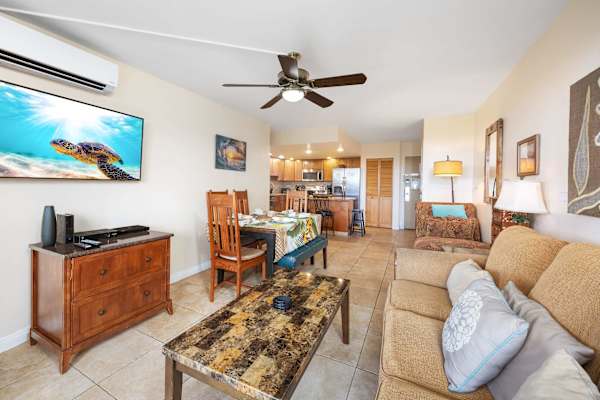 The living and dining area features a chaise lounge sofa, dining table for six, a pull‑out sleeper sofa, plus split‑type air conditioning and a 50" Samsung TV—providing a refined setting for dining, relaxation, and accommodating extra guests.