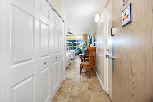 The unit features two queen-size beds, a 42" Samsung TV, split air-conditioning and a ceiling fan, a dresser and nightstand, direct access to a bathroom with a walk-in shower, and private lanai (balcony) access.