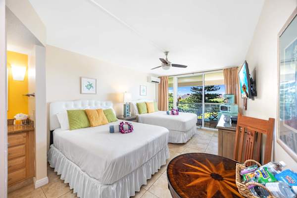 The unit features two queen-size beds, a 42" Samsung TV, split air-conditioning and a ceiling fan, a dresser and nightstand, direct access to a bathroom with a walk-in shower, and private lanai (balcony) access.