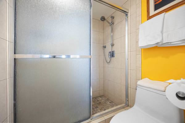 Find a clean and sanitized bathroom with a comfortable toilet seat, shower separated with a glass door for quick luxury, and toiletries for guests' convenience.
