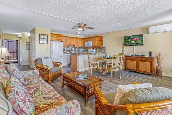 Airy open-concept living room w/ sofa seating, dining table & full kitchen. Split AC