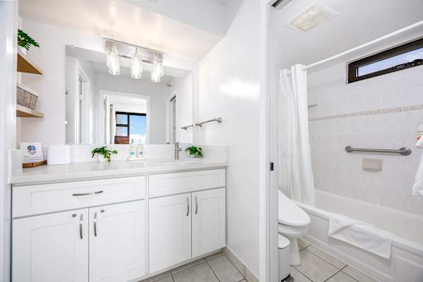 Freshen up conveniently in this spacious sink area featuring a wide mirror and bright vanity lights.