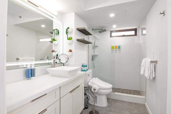 Bright bathroom w/ walk-in shower, vanity sink & large mirror