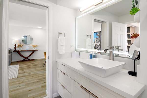 Bathroom vanity area w/ modern vessel sink, large mirror & bright lighting
