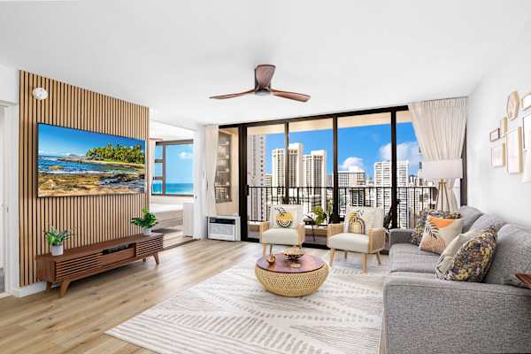 Bright living area w/ floor-to-ceiling windows & balcony access showcasing ocean & city views