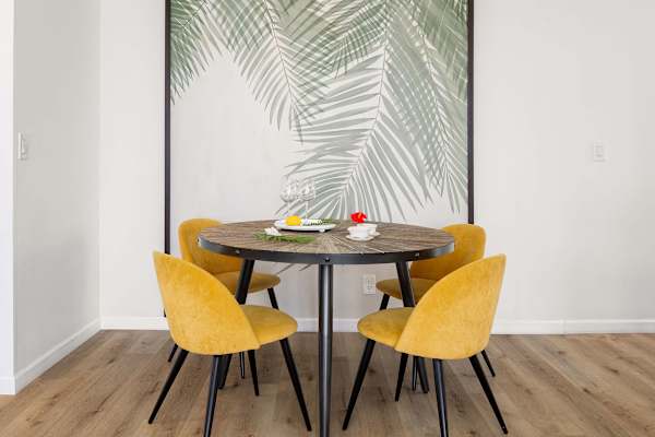 Round dining table w/ four chairs set against a tropical leaf accent wall