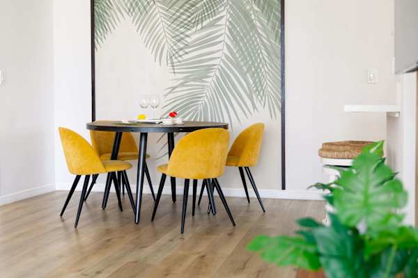 Round dining table w/ four chairs set against a tropical leaf accent wall