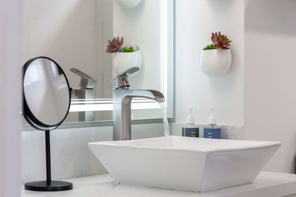 Sleek vessel sink vanity w/ modern faucet & wall planters adding a fresh touch
