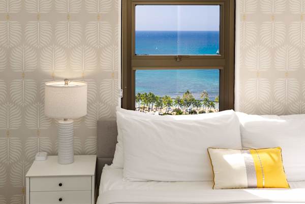 Bedroom corner w/ bedside table & window framing calming ocean views