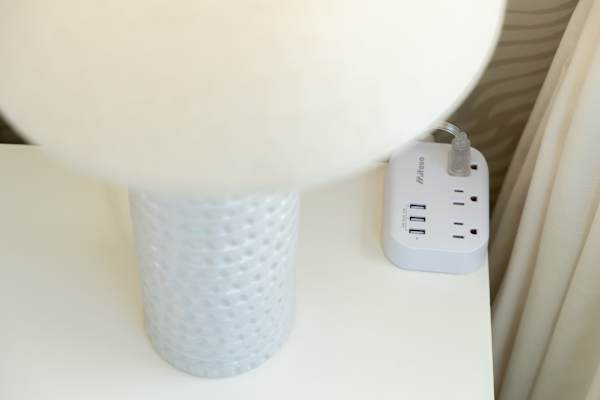 Bedside table w/ lamp & nearby power outlets for convenient device charging