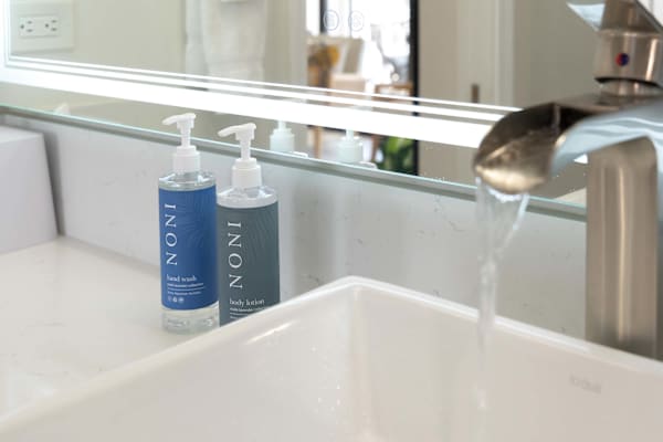 Bathroom vanity detail w/ modern sink, faucet & toiletries