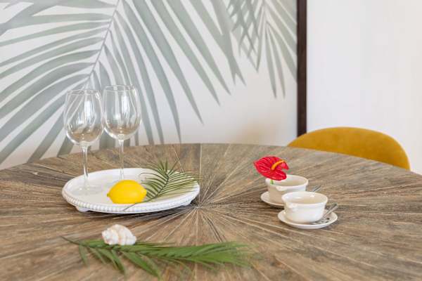 Dining table styled for a cozy meal w/ plates, cups & tropical décor