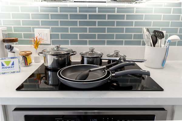 Cooktop setup w/ pots, pans & utensils ready for home-cooked meals