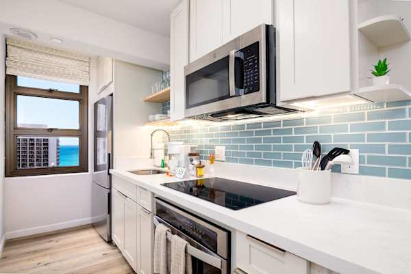 Sleek galley kitchen w/ modern appliances, tile backsplash & window views