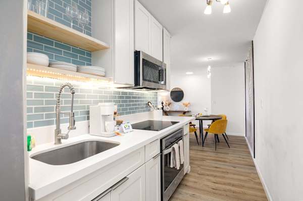 Modern kitchen w/ sink, tile backsplash, microwave & cozy dining nook