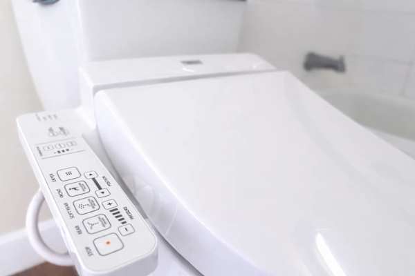 Your bathroom has a modern toilet with a bidet control panel
