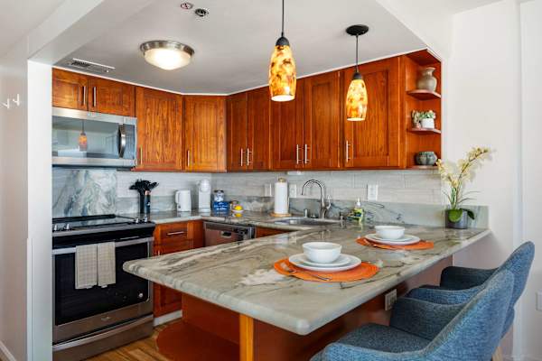 The kitchen counter doubles as a cozy dining spot for two, perfect for meals or quick morning coffee.