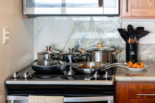 Cook with ease in your well-equipped kitchen space, featuring a sleek glass-top range, modern stainless steel cookware, and a stylish, functional setup.