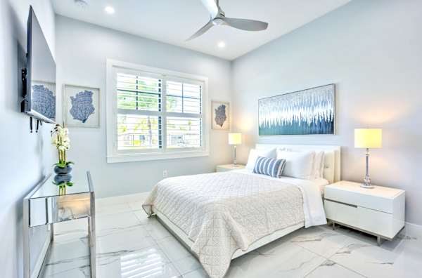 Modern Bedroom Featuring A Comfortable Queen Bed, Natural Light, Ceiling Fan, And Sleek Finishes