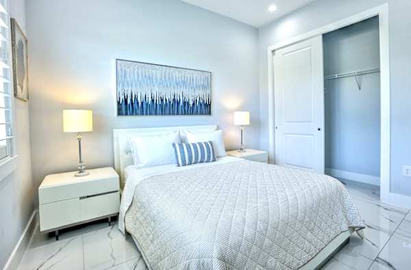 Modern Bedroom Featuring A Comfortable Queen Bed, Natural Light, Ceiling Fan, And Sleek Finishes