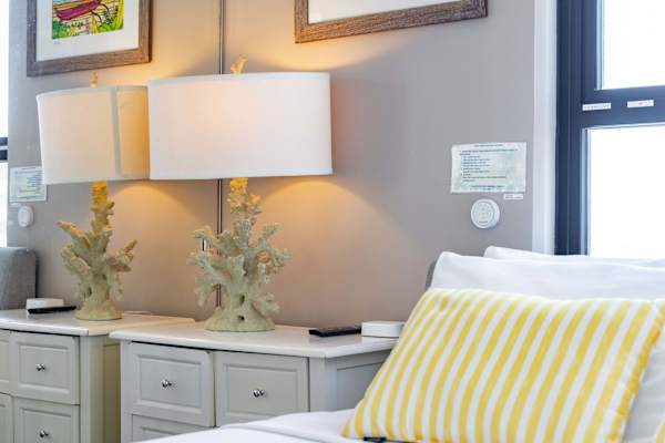 coral-inspired lamp on a white bedside table next to a window with natural light