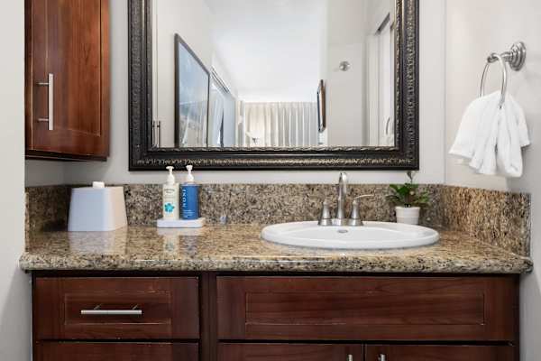 Freshen up conveniently in this spacious sink area featuring a wide mirror and bright vanity lights.
