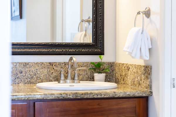 Freshen up conveniently in this spacious sink area featuring a wide mirror and bright vanity lights.
