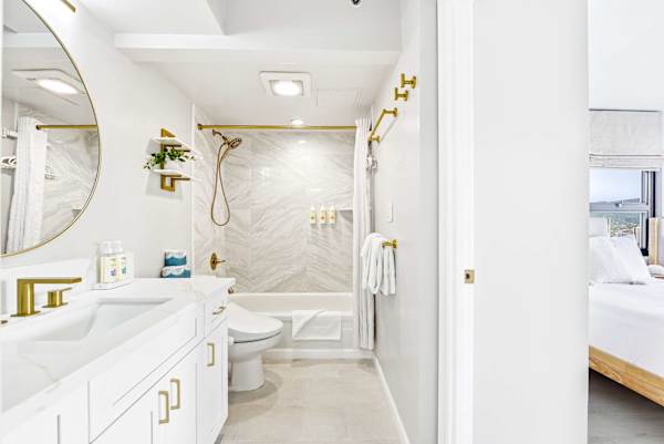 Your bright and airy en-suite bathroom features modern white finishes, elegant gold accents, and a marble-tiled shower.