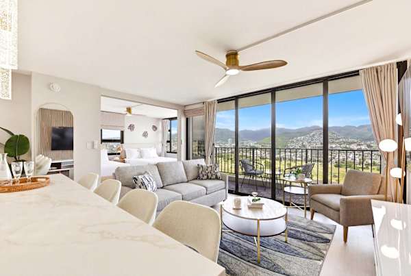 This elegant open-concept layout seamlessly connects the kitchen bar to the living area and private balcony, all framed by breathtaking mountain views.