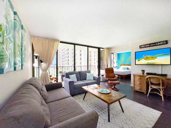 A welcoming living area featuring a pull-out sleeper sofa, a couch, a stylish wood coffee table, an entertainment center, and sliding glass doors leading to a balcony view.
