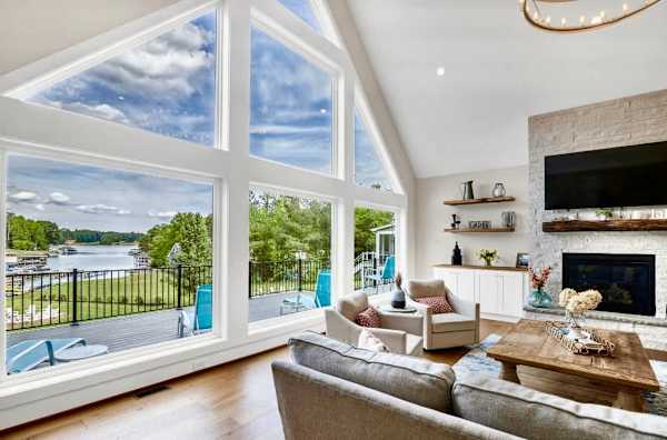 Great Room - Our two story vaulted ceilings & wall of windows fill the living room with natural light, anchored by our white stone fireplace & live edge rustic mantle with wood from an 1800's log cabin! So many authentic antiques fill Blueberry Bay!